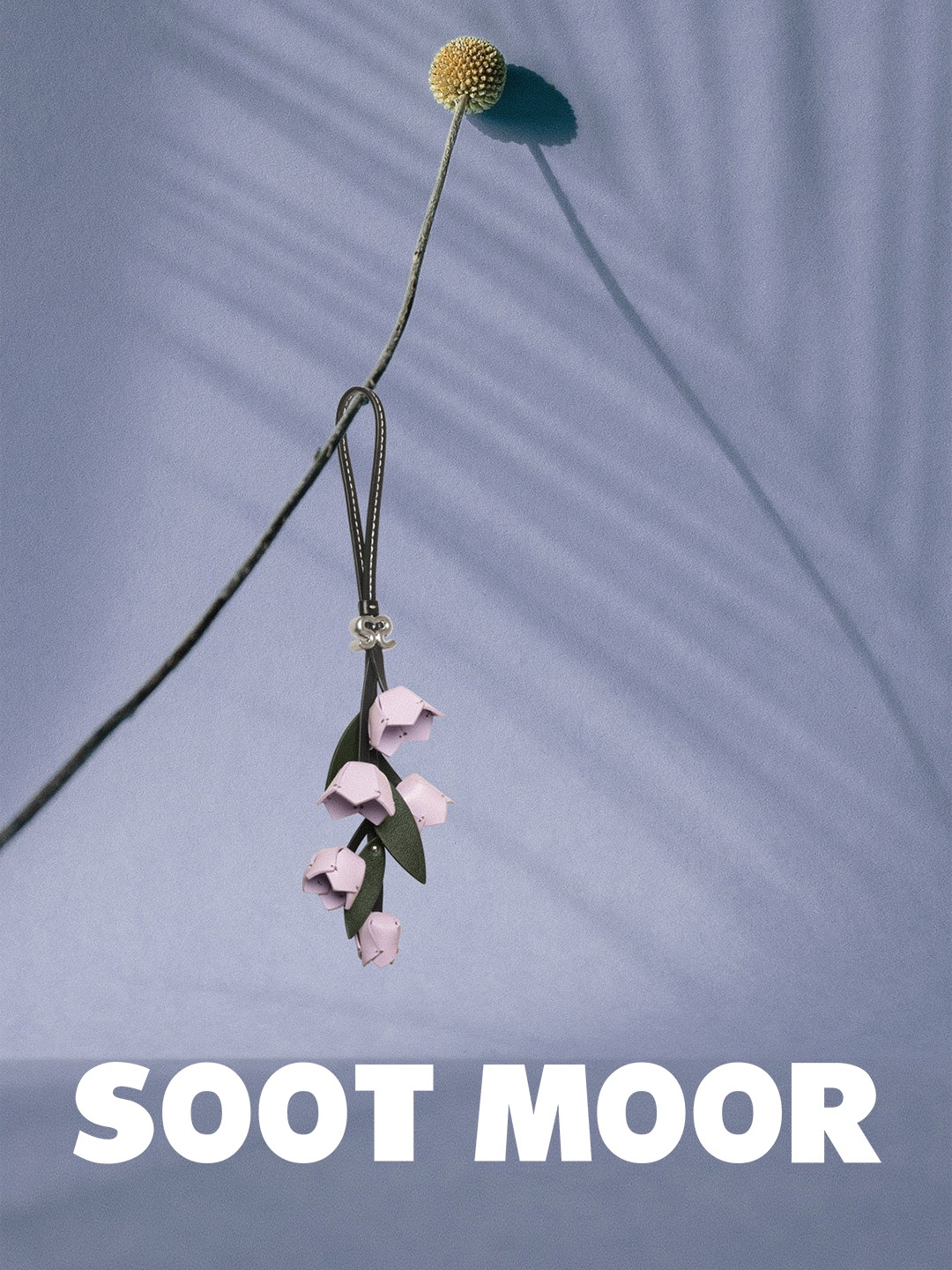 SOOT MOOR floral accessory suspended against a lilac background